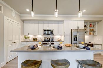Quartz Countertops with Undermount Stainless Steel Farmhouse Sinks and Subway Tile Backsplashes